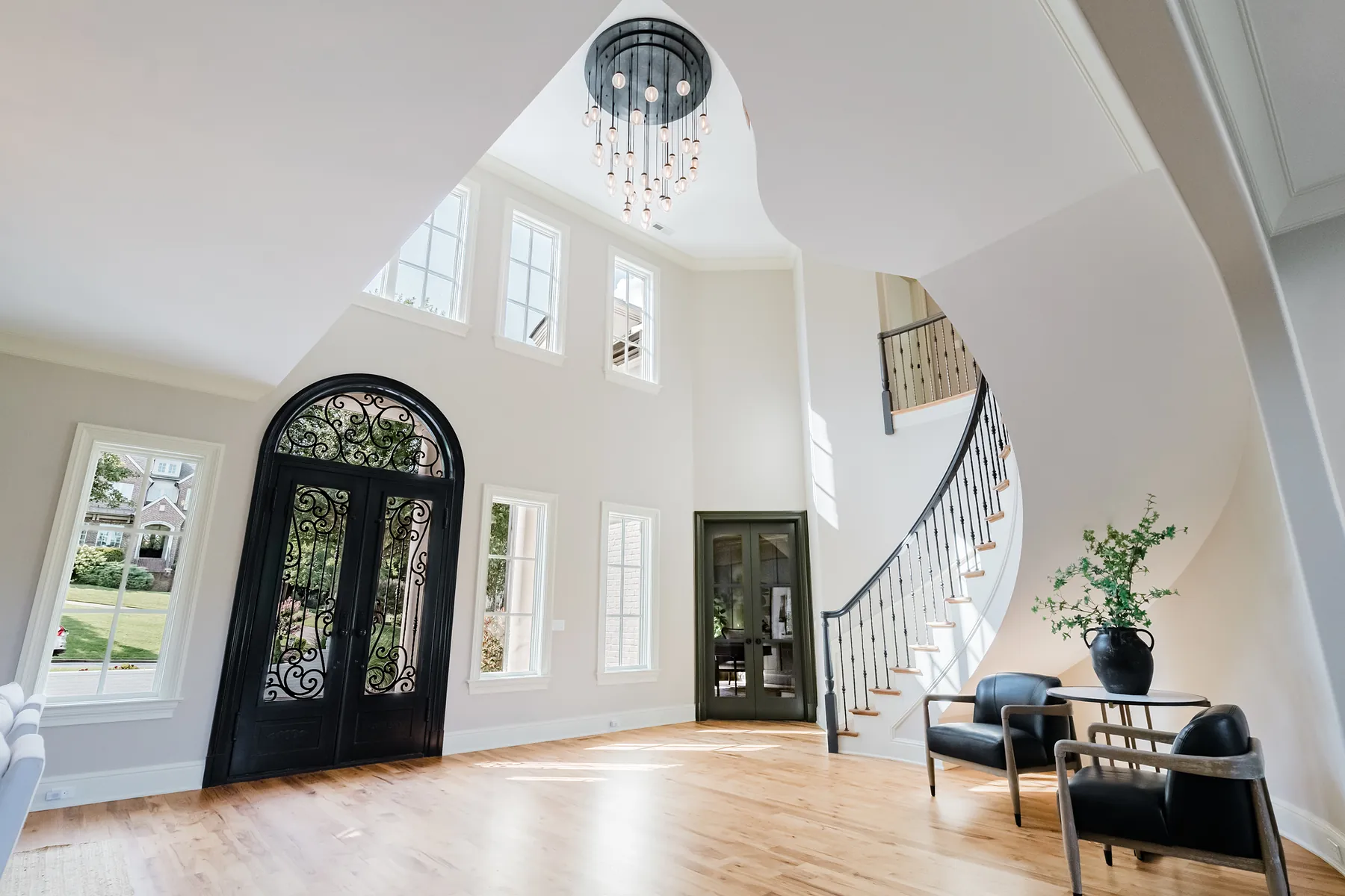 Two-story entry hall with iron and glass front doors and a curved staircase