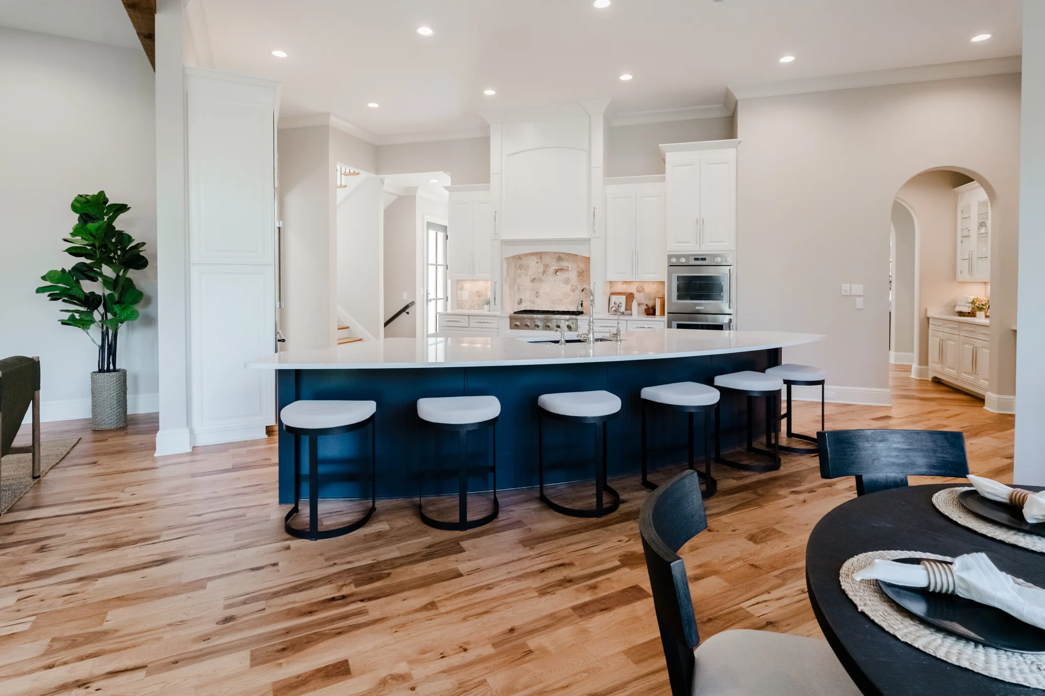 Wide Oxmoor kitchen with a navy island, white cabinetry, and an arched pantry opening