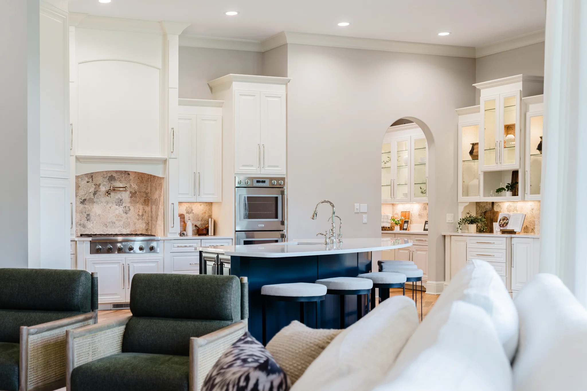 Oxmoor kitchen with white cabinetry, a navy island, and living-room seating in the foreground