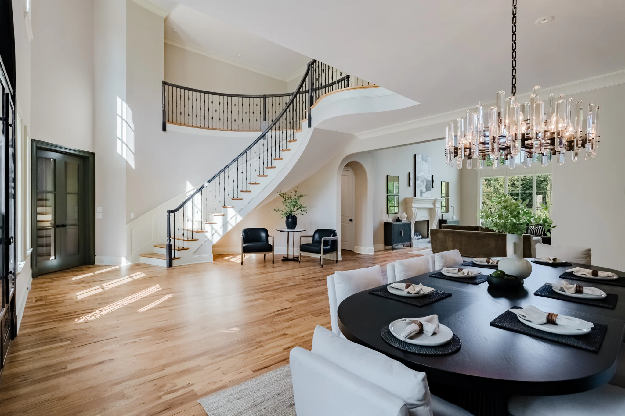 Open-plan Oxmoor interior with a curved staircase, dining area, and living room beyond